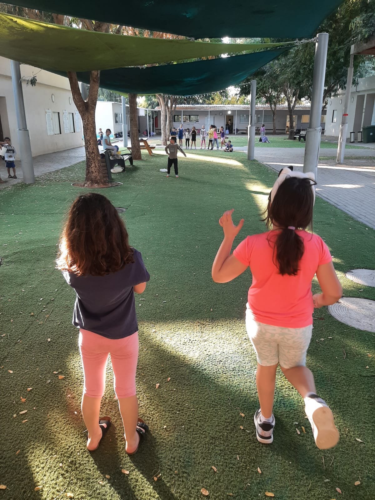 שתי ילדות רצות על הדשא, מצולמות מאחור